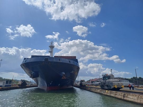 Un imposant porte-conteneurs dans une écluse du canal de Panama, guidé par les Mulas